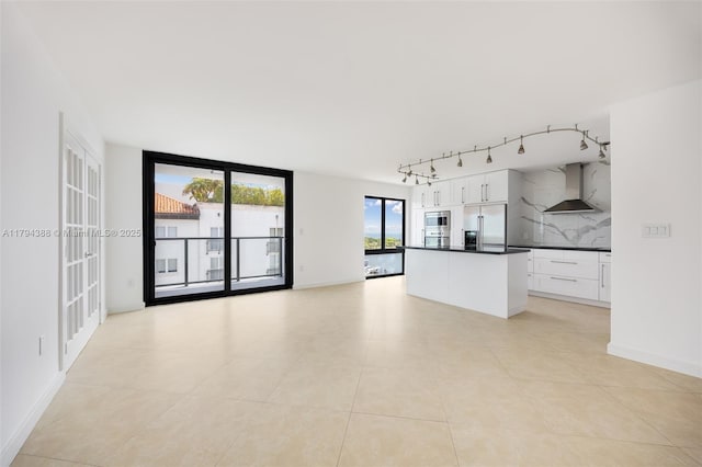 unfurnished living room featuring light tile patterned flooring, rail lighting, and baseboards