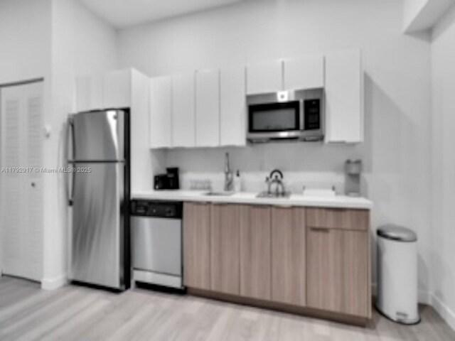 136 NW 26th St Unit 503, Miami, FL 33127 - kitchen with light countertops, baseboards, stainless steel appliances, and white cabinetry