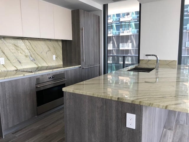 801 S Miami Ave Unit 2505, Miami, FL 33130 - kitchen featuring light stone countertops, a sink, stainless steel oven, white cabinetry, and modern cabinets