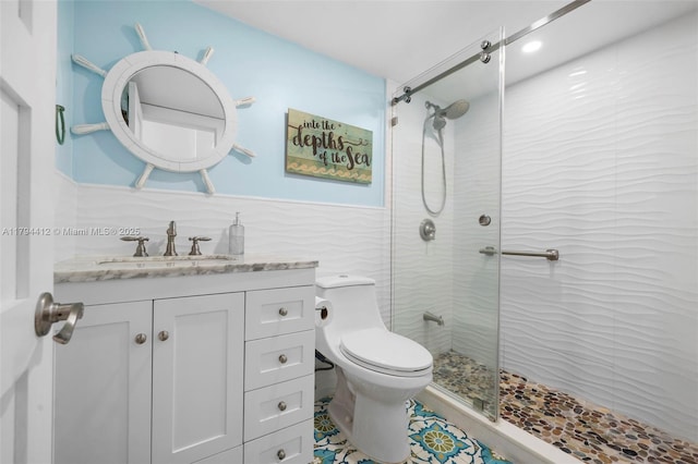 full bath with toilet, tile walls, tiled shower, and vanity