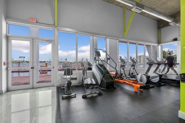gym featuring french doors, a city view, a high ceiling, and visible vents