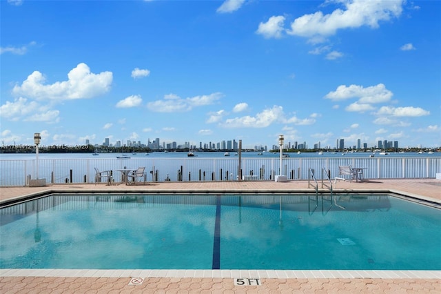 community pool with fence and a city view