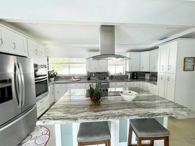 416 N Rainbow Dr, Hollywood, FL 33021 - kitchen with stainless steel appliances, island range hood, a kitchen breakfast bar, and white cabinets