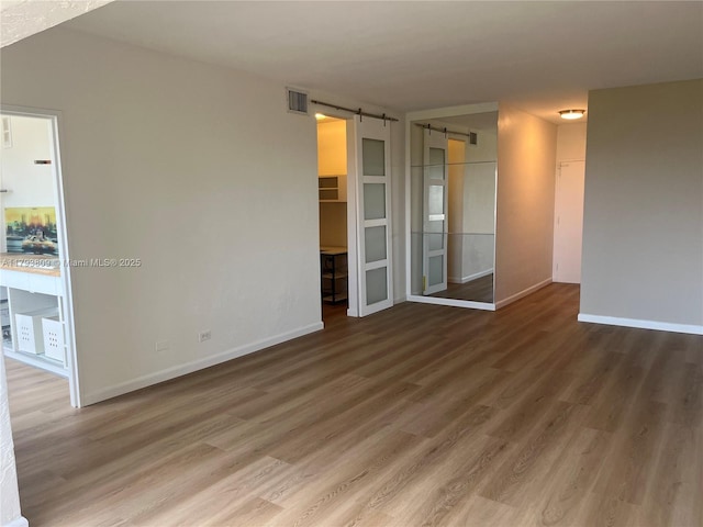 3 Island Ave Unit 08A, Miami Beach, FL 33139 - empty room featuring a barn door, wood finished floors, and baseboards