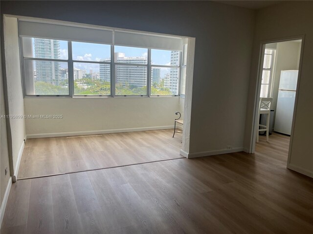 3 Island Ave Unit 08A, Miami Beach, FL 33139 - spare room featuring wood finished floors, baseboards, and healthy amount of natural light
