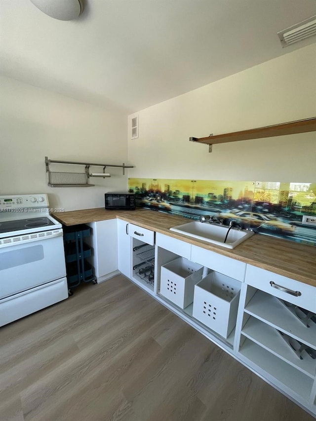 kitchen with visible vents, butcher block counters, black microwave, white electric range, and light wood finished floors