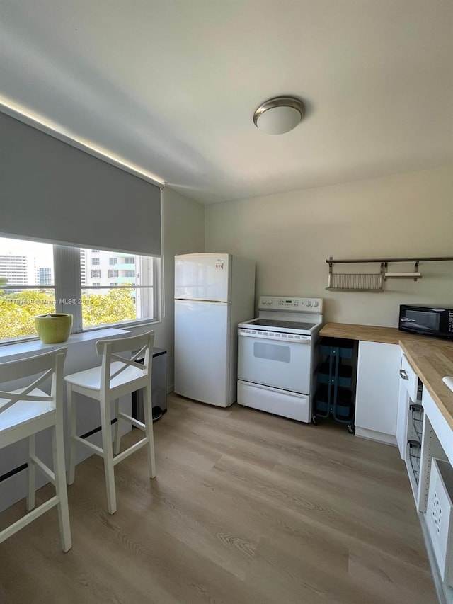kitchen featuring white appliances, white cabinets, and light wood-style flooring