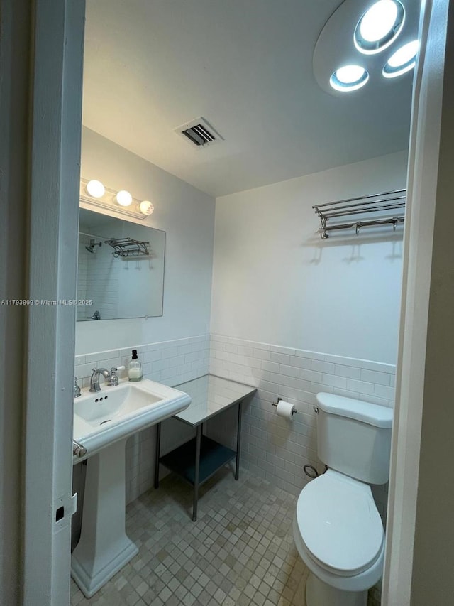 bathroom with visible vents, tile patterned flooring, wainscoting, toilet, and tile walls