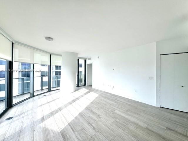 spare room featuring floor to ceiling windows and light wood-style flooring