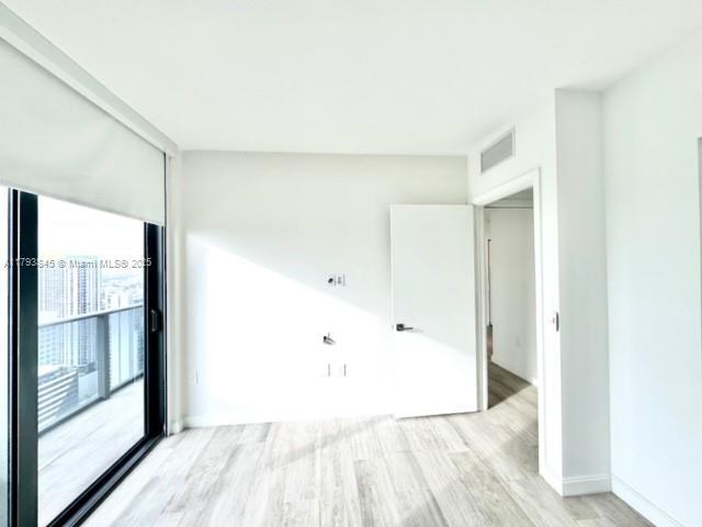 empty room featuring baseboards, visible vents, and light wood-style floors