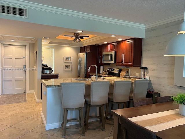 kitchen featuring visible vents, crown molding, a peninsula, appliances with stainless steel finishes, and light tile patterned floors
