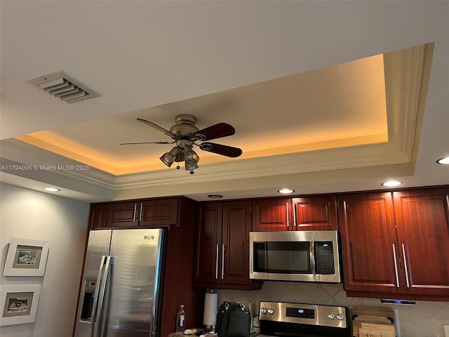 kitchen featuring appliances with stainless steel finishes, ceiling fan, a tray ceiling, and recessed lighting