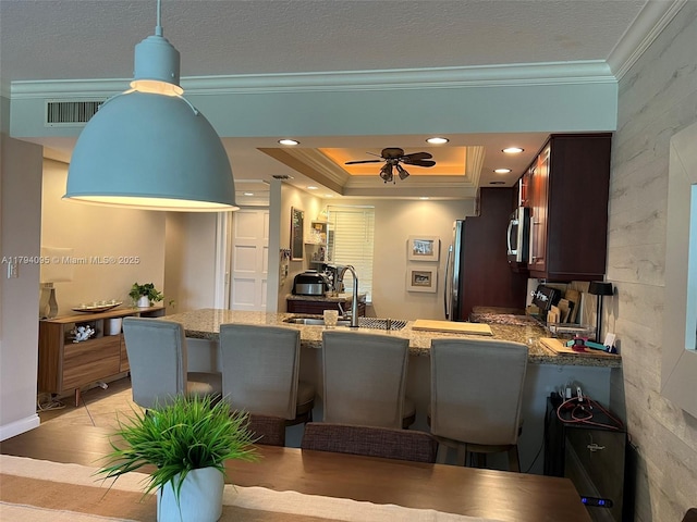 kitchen featuring crown molding, a peninsula, a breakfast bar area, a sink, and stainless steel appliances