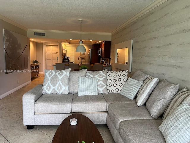 living room featuring crown molding, light tile patterned flooring, and a textured ceiling
