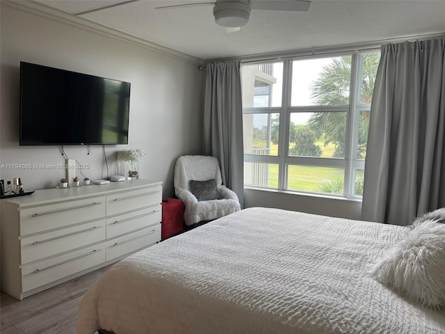 bedroom with light wood-style floors, ornamental molding, and ceiling fan