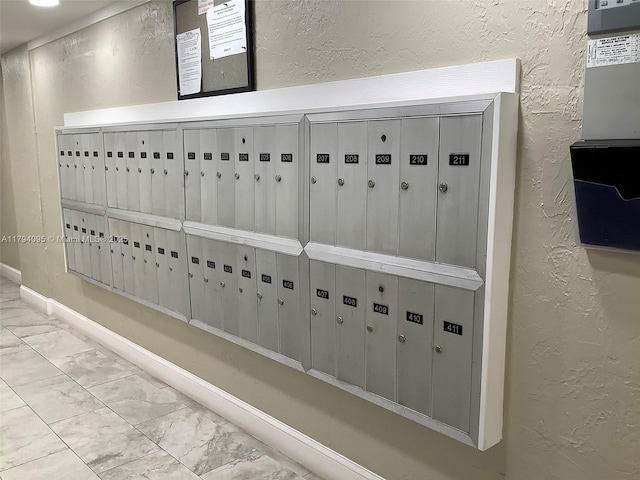 details featuring baseboards, a textured wall, and mail area