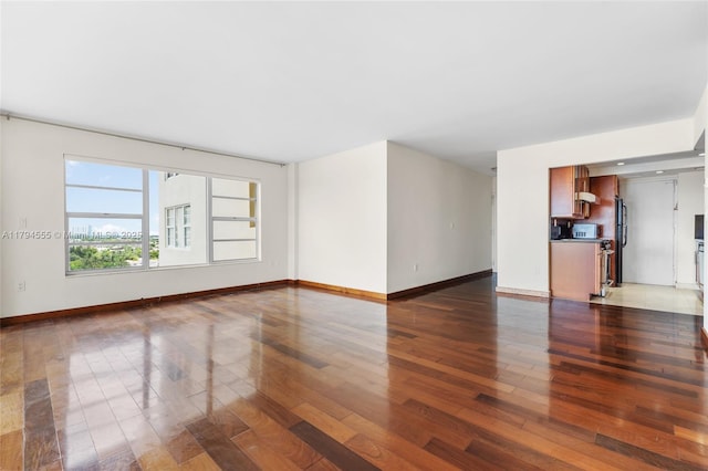 unfurnished living room with baseboards and dark wood-type flooring