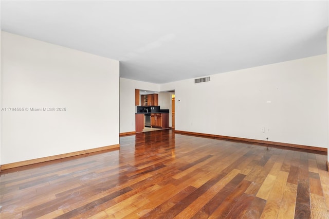 spare room with baseboards, visible vents, and hardwood / wood-style flooring