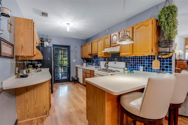 9341 Marine Dr, Cutler Bay, FL 33189 - kitchen featuring tasteful backsplash, light wood-type flooring, light countertops, under cabinet range hood, and white appliances