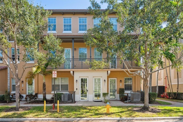 back of property featuring french doors, central air condition unit, stucco siding, and a balcony