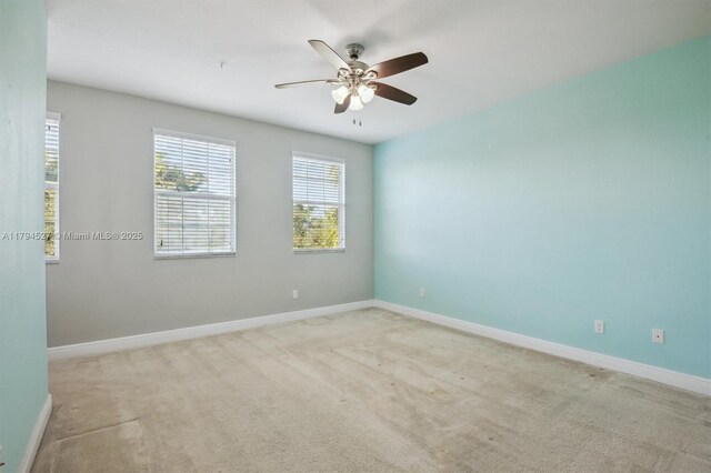 carpeted spare room featuring baseboards and ceiling fan
