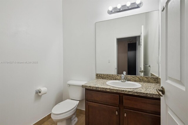 bathroom with toilet, baseboards, tile patterned floors, and vanity