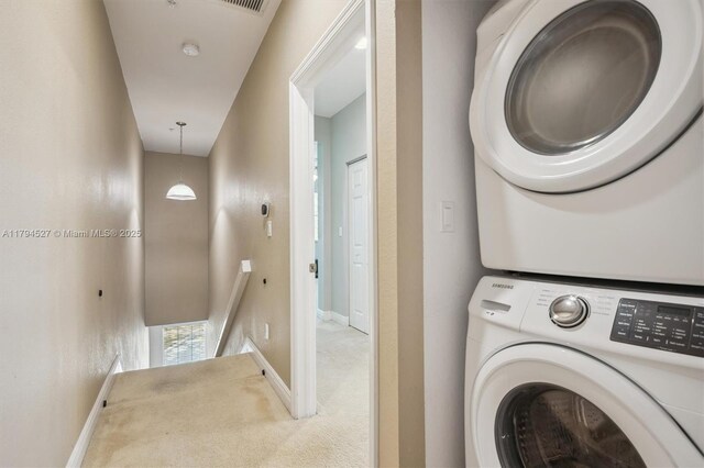 washroom with baseboards, stacked washer and clothes dryer, carpet flooring, and laundry area