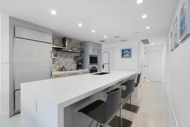 3801 Collins Ave Unit 703, Miami Beach, FL 33140 - kitchen with wall chimney range hood, decorative backsplash, a sink, light countertops, and recessed lighting