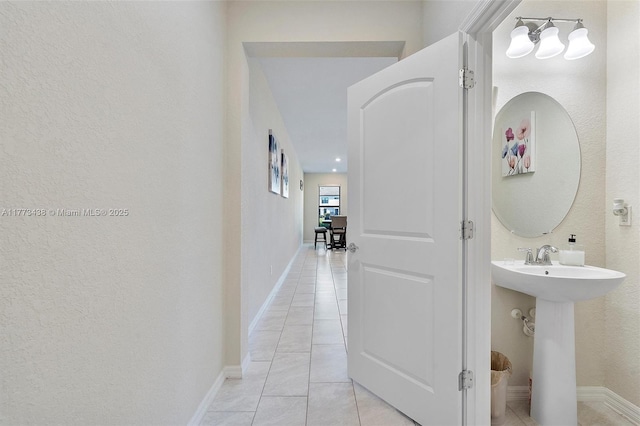 bathroom featuring baseboards, a sink, a textured wall, and tile patterned floors