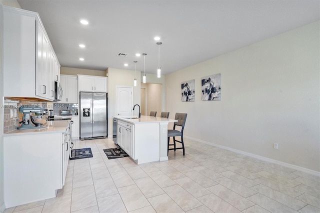 kitchen with light countertops, stainless steel appliances, a kitchen bar, and visible vents