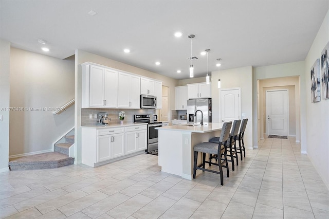 kitchen with a kitchen breakfast bar, a kitchen island with sink, tasteful backsplash, light countertops, and stainless steel appliances