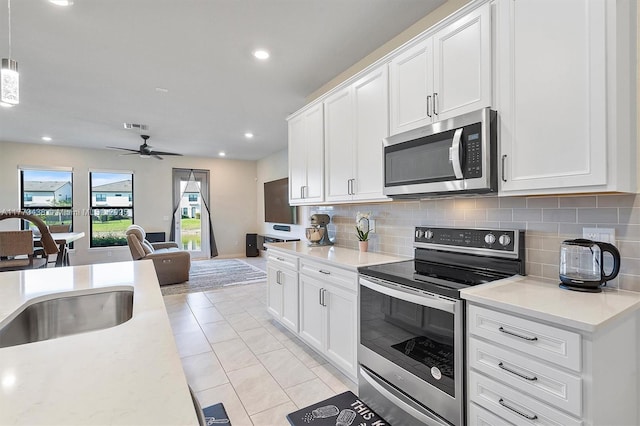 kitchen with light countertops, stainless steel appliances, a sink, and tasteful backsplash