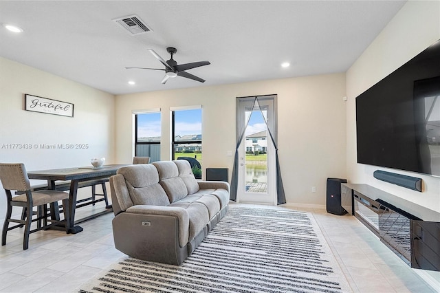 living area featuring a healthy amount of sunlight, light tile patterned floors, a ceiling fan, and visible vents
