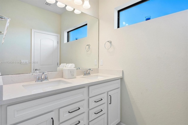 bathroom featuring visible vents, a sink, and double vanity