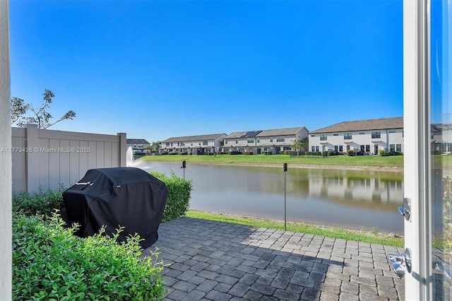 view of patio featuring a water view, a residential view, and a grill