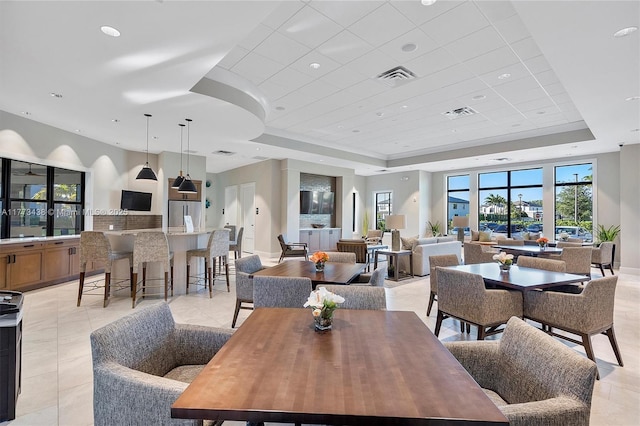 dining area featuring light tile patterned flooring, baseboards, visible vents, and a raised ceiling