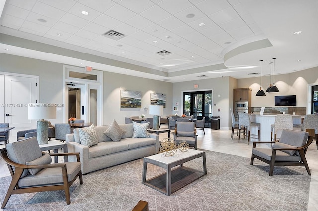 living area featuring a raised ceiling, recessed lighting, and visible vents