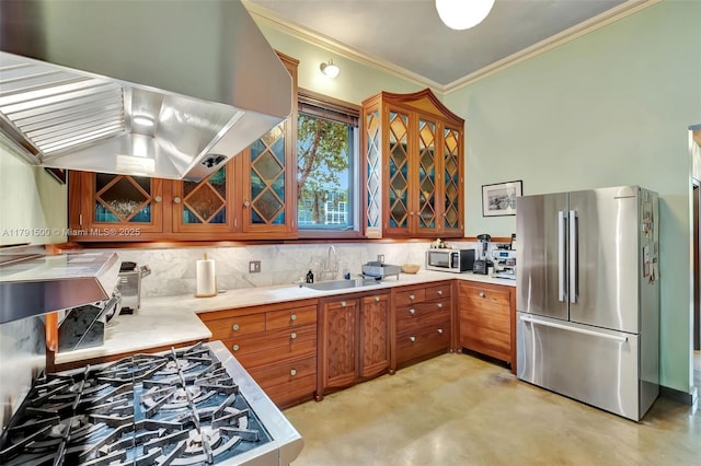 kitchen with brown cabinetry, range hood, tasteful backsplash, a sink, and stainless steel appliances
