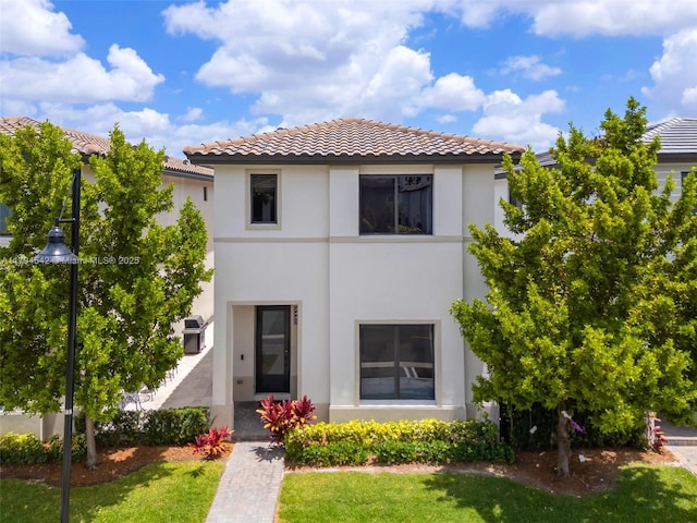 view of front of property featuring a tiled roof, a front yard, and stucco siding
