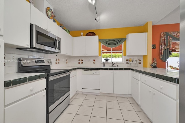 13230 NW 10th St, Miami, FL 33182 - kitchen featuring a textured ceiling, appliances with stainless steel finishes, tasteful backsplash, white cabinets, and tile counters