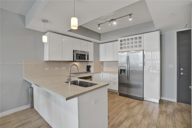 kitchen with stainless steel appliances, baseboards, light wood finished floors, and a peninsula