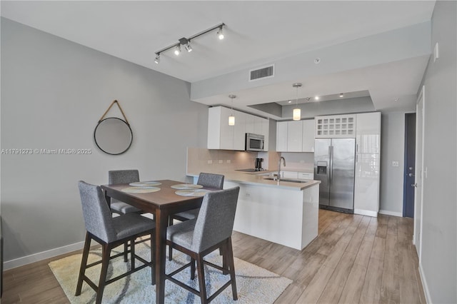 kitchen with appliances with stainless steel finishes, a sink, baseboards, white cabinets, and a peninsula