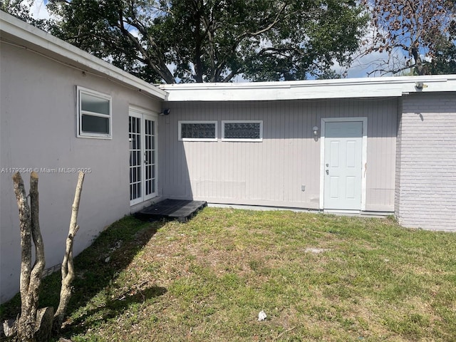 property entrance featuring a lawn and brick siding