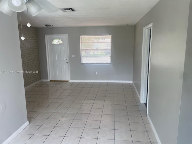 entryway featuring baseboards, ceiling fan, visible vents, and light tile patterned floors