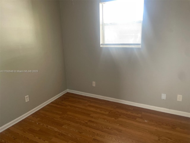 spare room featuring baseboards and wood finished floors