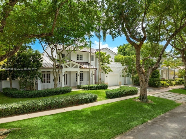 730 Santurce Ave, Coral Gables, FL 33143 - view of front of home featuring concrete driveway, a front lawn, covered porch, a standing seam roof, and metal roof