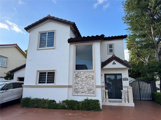 view of front of property featuring a tiled roof, a gate, and stucco siding