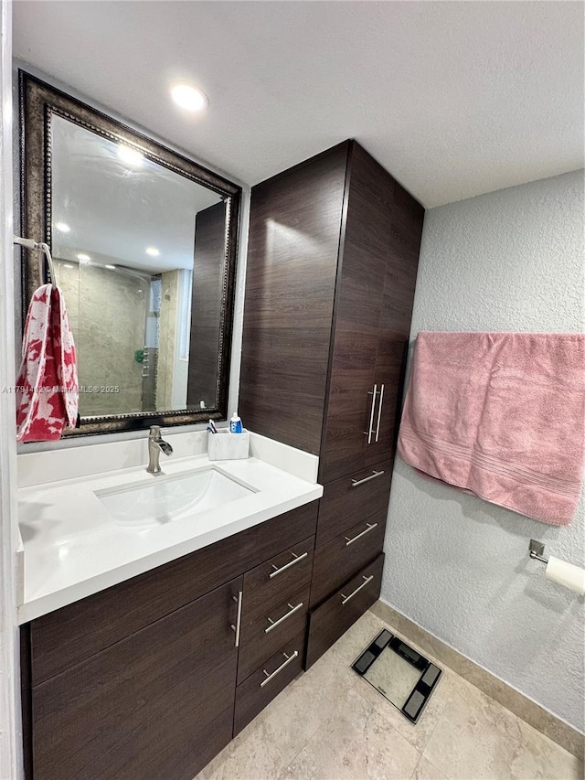bathroom with vanity, a textured wall, and a stall shower