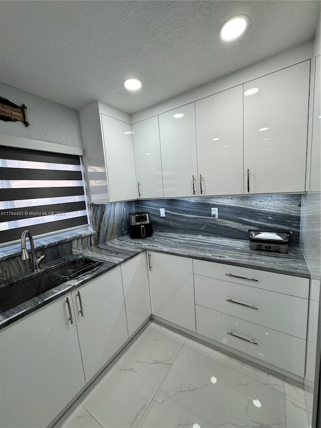 kitchen featuring marble finish floor, modern cabinets, recessed lighting, white cabinetry, and a textured ceiling