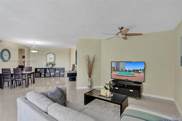 living area with ceiling fan, visible vents, baseboards, and tile patterned floors